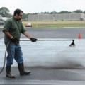 A professional applicator applies coal-tar-based sealcoat to a test plot used to measure emission of polycyclic aromatic carbons (PAHs) into the air