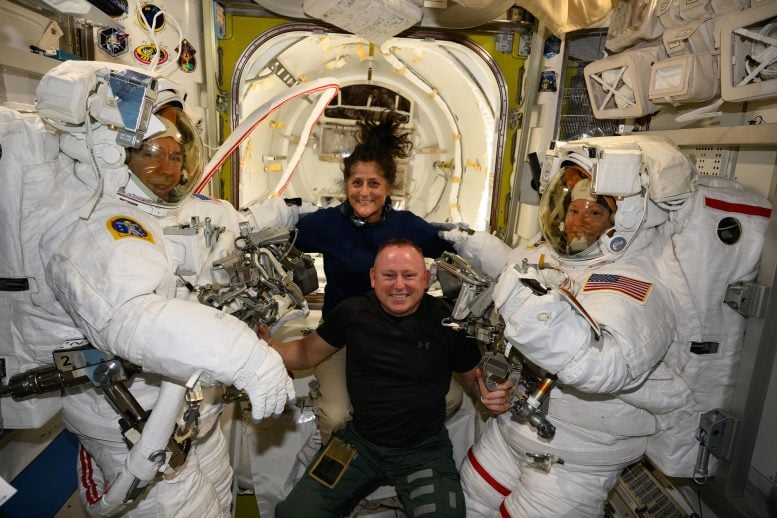 Astronauts help astronauts inside the airlock at the Quest station.