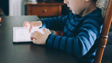 Boy Playing on Tablet at Table