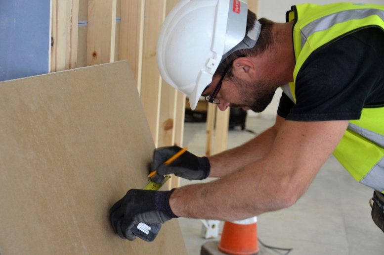 Builder Measuring Plasterboard