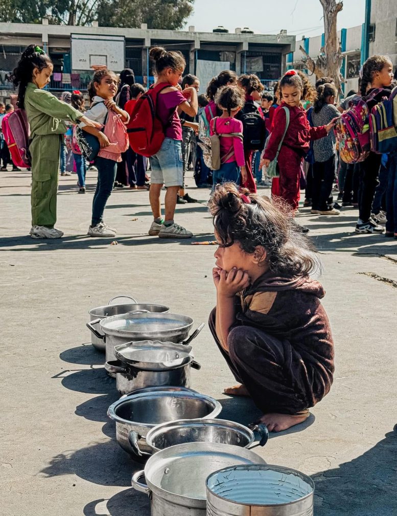 Gaza Child Crouches Next to Pots and Pans