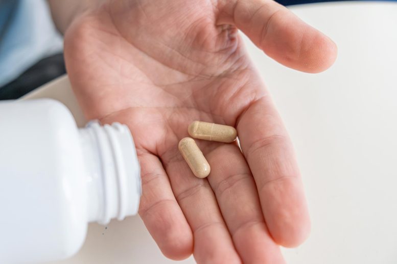 Man Pouring Probiotic Vitamin Nutrition Supplement Capsules Into Hand