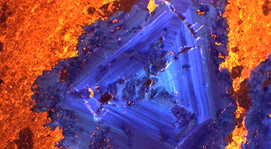 True-colour cathodoluminescence image taken with the Cameca SX100. Fluorite (blue-violet) is shown associated with calcite (yellow-orange) in a carbonatite from India. Credit: Natural History Museum UK